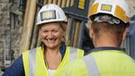 Picture shows a construction worker laughing into the camera. 