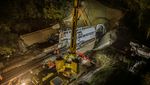 Preparatory tunnelling work with a crane at night at a tunnel entrance.
