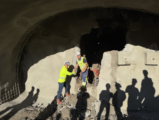 Zwei Bauarbeiter reichen sich die Hand vor einem frisch durchbrochenen Tunnelabschnitt â Symbol fĂŒr erfolgreichen Durchbruch im Tunnelbau