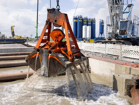 Bild zeigt einen Kran, der in der Baugrube baggert.